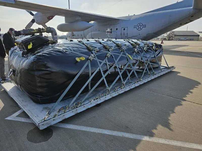 Secured cargo pallet beside military transport aircraft