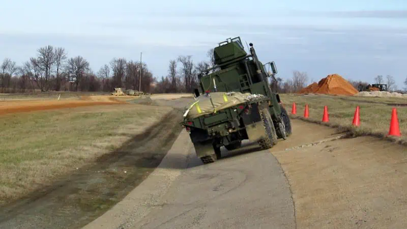 Military vehicle tilting on uneven dirt road