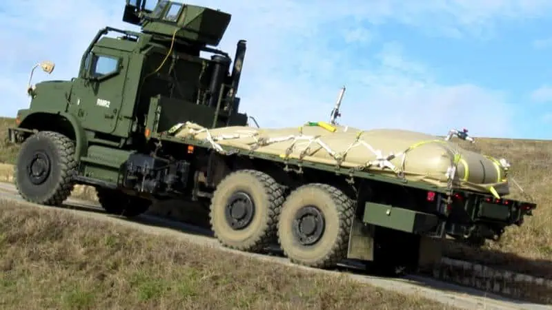 Military transport truck hauling heavy equipment uphill