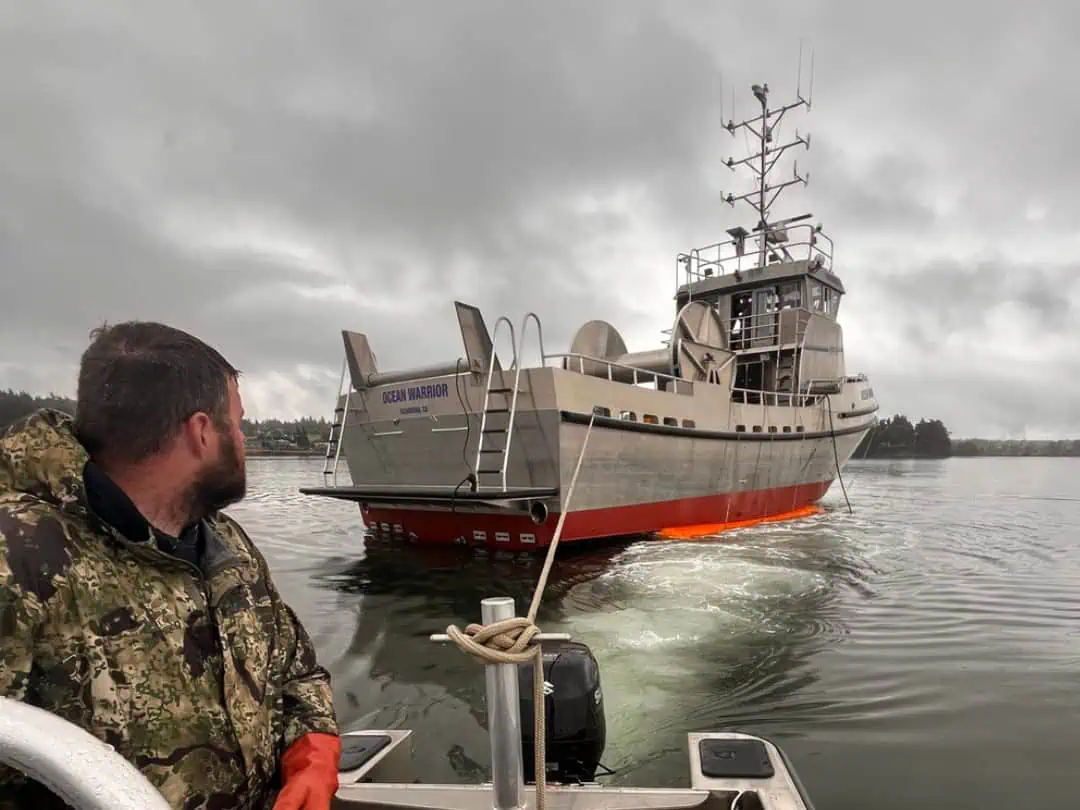 Man on small boat near large vessel