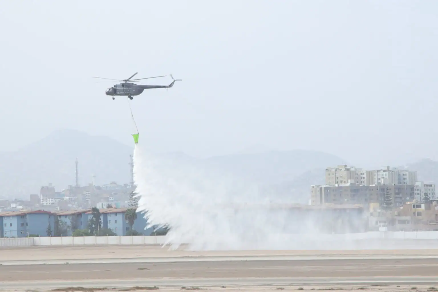 Helicopter releases water from bucket over urban area